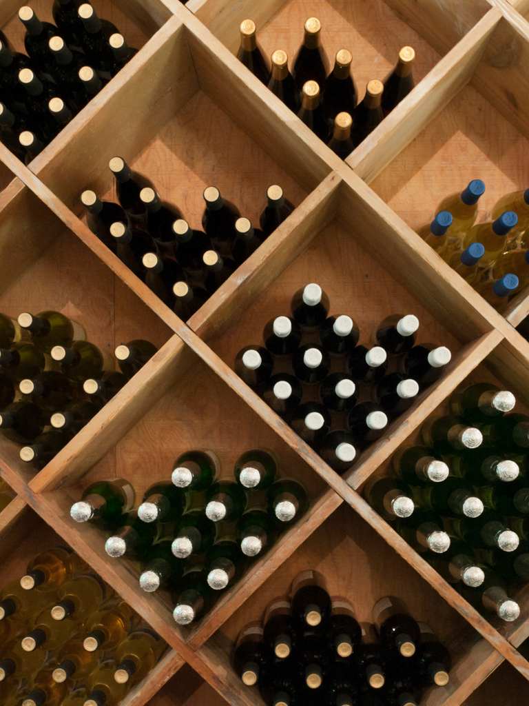 wine bottles stored on their side on wine shelves 